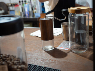 manual coffee grinder on the table surrounded by coffee storage and coffee processing tools