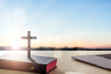Silhouette wooden cross on holy bible  sunrise background