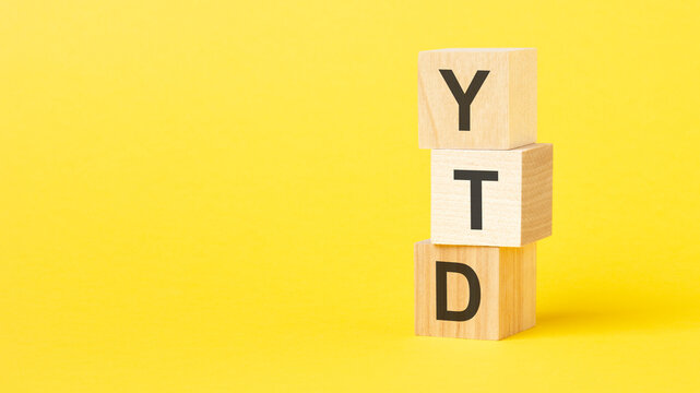 wooden blocks with the text YTD - short for year-to-date on a bright yellow background