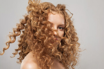 Glamorous wavy hair woman. Young fashion model with long curly hairstyle and natural fresh clear...