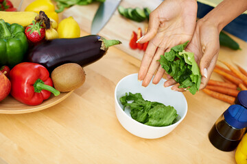 Woman, hands and bowl of lettuce in kitchen for salad, diet or natural nutrition on wooden table at home. Closeup of female person or vegetarian preparing vegetables for vegan meal or healthy snack