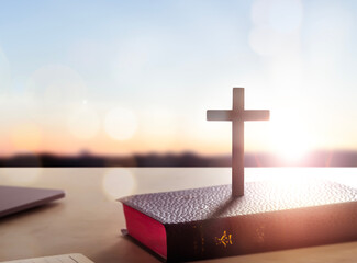 Silhouette wooden cross on holy bible  sunset background