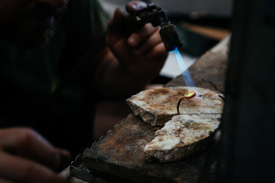 Jeweler soldering on work bench a gold ring bracelet with flame from welding torch in an authentic jewelry workshop