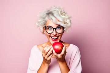 Mature woman with surprising expression holding a red apple. - obrazy, fototapety, plakaty