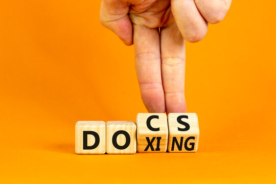 Docs or doxing symbol. Concept words Docs Doxing on wooden block. Beautiful orange table orange background. Businessman hand. Business docs or doxing concept. Copy space.