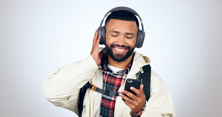 Man, travel and listening with headphones and phone for music in studio, white background or audio...