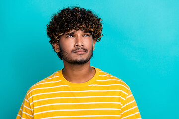 Photo portrait of attractive young man look unsure empty space wear trendy striped yellow clothes isolated on aquamarine color background