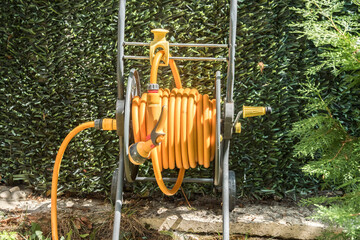 Yellow garden hose reel closeup in house backyard 