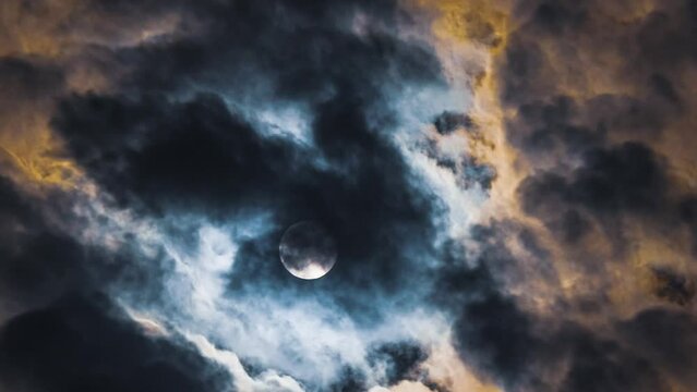 Full moon in terribly beautiful clouds. Time lapse. Black and yellow colours of clouds that move against the full moon