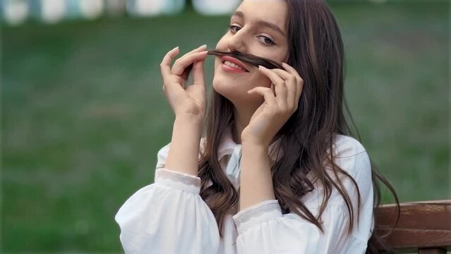 Portrait shot of cute happy funny woman smiling and flirting, depicting mustache from lock of hair. Beauty and organic hair care treatment, cosmetics, shampoo