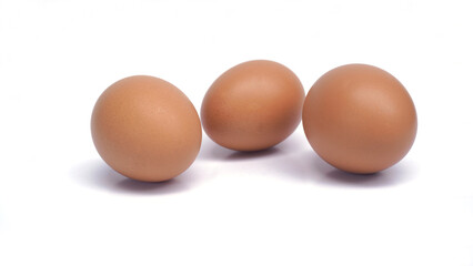 Group of raw brown chicken eggs, one broken, yellow egg photographed from the front, over a white background, empty area for text, copy space, pile of chicken eggs isolated on white background