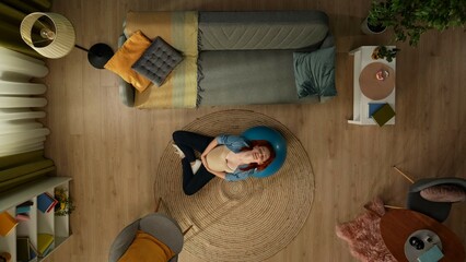 In the shot above, a pregnant woman is lying leaning on a fitness ball. She is doing a maternity fitness class. Closing her eyes she is smiling and relaxed. Expecting a new addition to the family