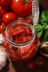 Jar of tasty tomato paste and ingredients on table, above view