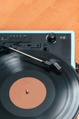 Obraz premium Vertical photo of a blue record player, on wooden table. Concept hobbies, art.