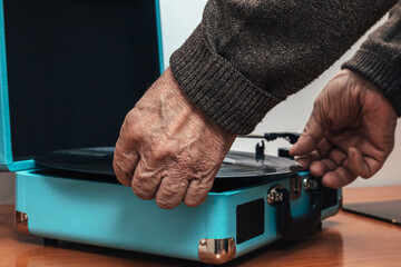 Horizontal close up photo senior adult man backside placing vinyl on a turntable Concept hobbies art