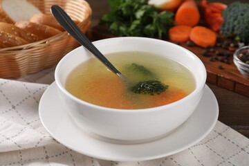 Tasty soup with vegetables in bowl served on wooden table, closeup