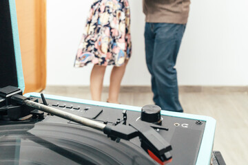 Extreme close up horizontal photo of record player and senior couple dancing. Concept hobbies, art.