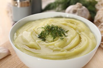Bowl of tasty cream soup with dill on wooden table, closeup