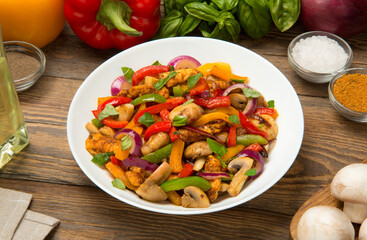 Chicken fried with bell peppers, mushrooms in a salad bowl on a wooden rustic table. - 671729363