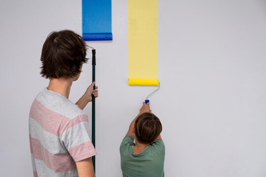children paint the wall with a roller. teenagers spend time together helping to make repairs.