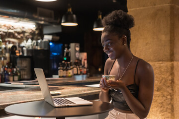 Young relaxed woman sitting on a bar during online meeting