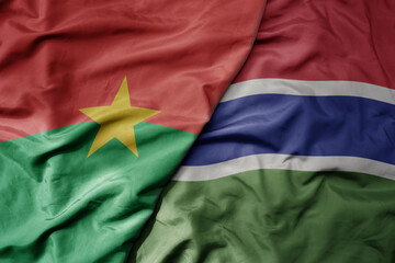 big waving national colorful flag of burkina faso and national flag of gambia .