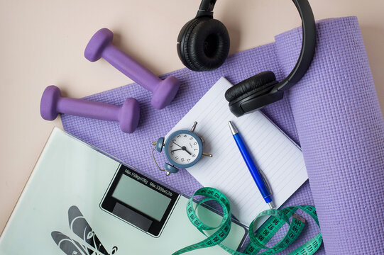 Healthy lifestyle, yoga, daily routine, training, weight, weight loss concept, daily routine control. Dumbbells, scales, watch, notepad and workout mat. Horizontal frame.