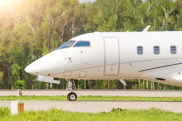 Obraz premium Close-up of the nose of a white passenger private business jet on the taxiway at the airport. The business jet is preparing to take off