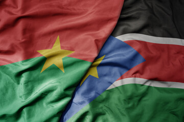 big waving national colorful flag of burkina faso and national flag of south sudan .