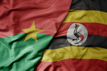 Fototapeta premium big waving national colorful flag of burkina faso and national flag of uganda .