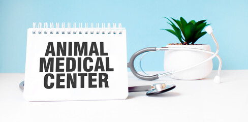 The text ANIMAL MEDICAL CENTER is written on notepad near a stethoscope on a blue background. Medical concept