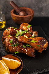 Chicken drumsticks with sesame seeds, Asian cooked chicken, black background vertical photo