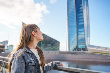 A teenage girl walks next to a high business tower in St. Petersburg