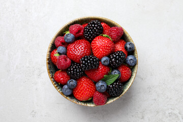 Different fresh ripe berries in bowl on light grey table, top view - Powered by Adobe
