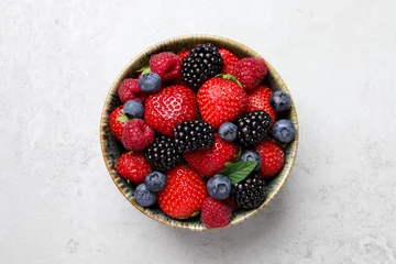 Fotobehang Different fresh ripe berries in bowl on light grey table, top view © New Africa