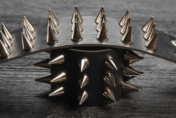 Black studded leather bracelet on the black wooden table background close up.