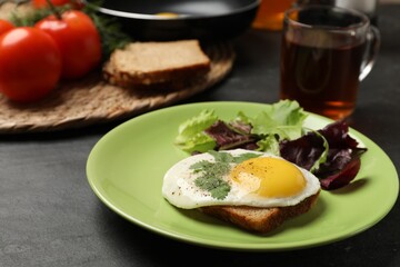 Delicious breakfast with fried egg and salad served on black table, closeup