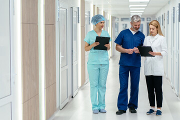 Medicine, healthcare and people concept. Surgeon and female doctor talking at hospital hallway....