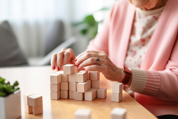 Faceless elderly woman with dementia playing with wooden blocks in geriatric clinic or nursing home close-up - obrazy, fototapety, plakaty