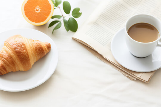 Delicious morning breakfast with freshly baked croissant, hot coffee and a newspaper