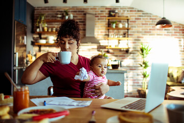 Mother sips her coffee while holding her curious baby amidst morning chores