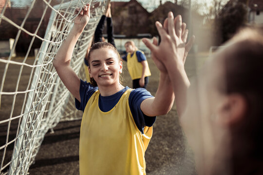 Young female football players high fiving on the pitch