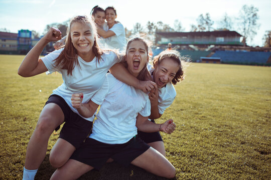 Young female football team celebrating a goal on the pitch