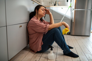 Exhausted woman takes a moment's rest after cleaning in the kitchen