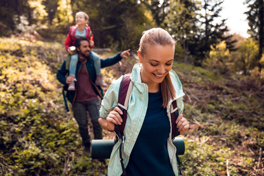 Joyful family hiking through the woods, with a child riding on her father's shoulders