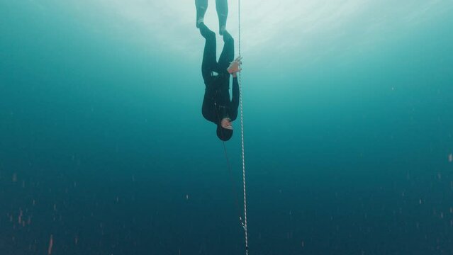 Freediving on a rope. Man freediver training along the rope in the sea and falling into the depth