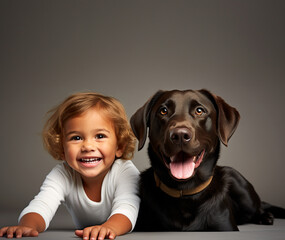 niño rubio feliz alado de un perro labrador negro 