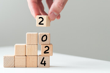 2024 in concept of wooden block numbers. Human hand holding block number isolated on white