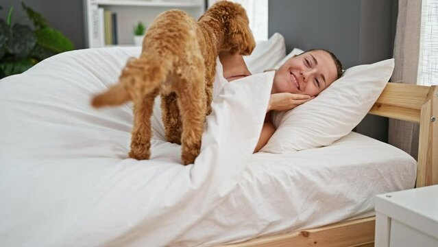 Young caucasian woman with dog lying on the bed together playing at bedroom