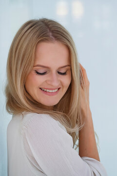 Portrait of attractive smiling young blonde woman with perfect smile. Pretty healthy young female with light natural face makeup inside white interior.